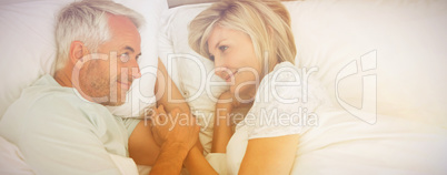 Loving mature man and woman lying in bed