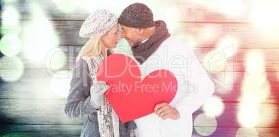 Composite image of couple holding heart while looking at each other