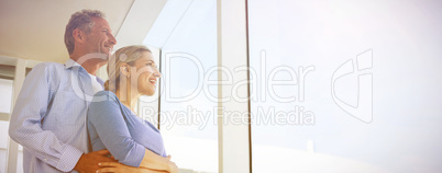 Couple looking through window at home