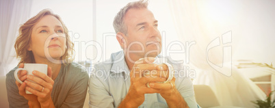 Thoughtful middle aged couple sitting on the couch having coffee