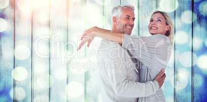 Composite image of cheerful husband embracing wife