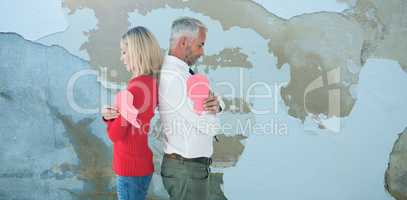 Composite image of couple holding two halves of broken heart