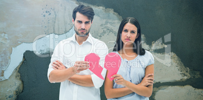 Composite image of upset couple holding two halves of broken heart