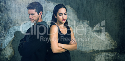 Composite image of sad couple with arms crossed standing back to back