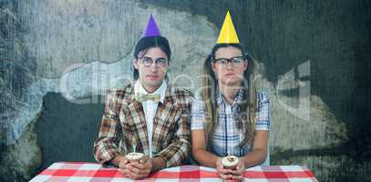 Composite image of unsmiling geeky hipsters celebrating birthday