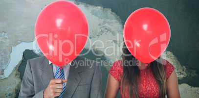 Composite image of geeky couple holding balloons in front of their faces