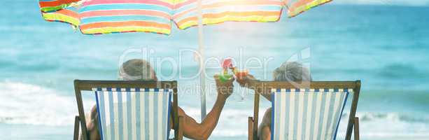 Cute mature couple lying on deckchairs