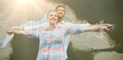 Composite image of happy couple standing with arms outstretched