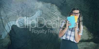 Composite image of geeky hipster hiding her face behind notepad