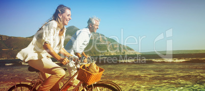 Smiling couple riding their bikes on the beach