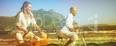 Smiling couple riding their bikes on the beach