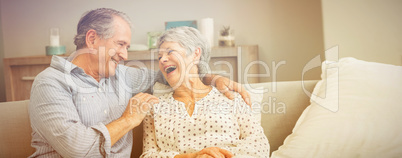 Romantic senior couple laughing while sitting on sofa