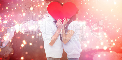 Composite image of couple covering their kiss with a heart