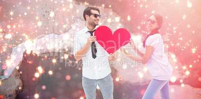 Composite image of hipster couple smiling at camera holding a heart