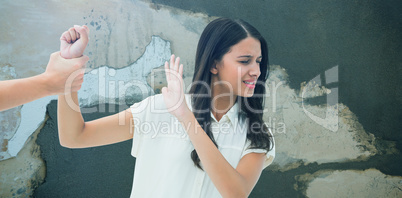Composite image of fearful brunette being grabbed by the hand