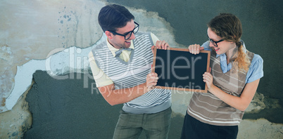 Composite image of geeky hipster couple holding little blackboard