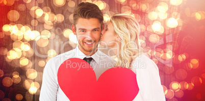 Composite image of attractive young couple holding red heart