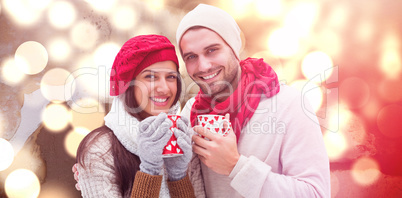 Composite image of winter couple holding mugs