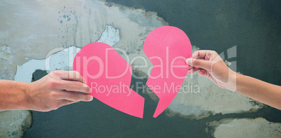 Composite image of hands holding two halves of broken heart