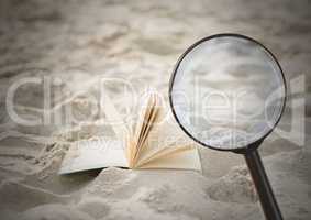 3D Magnifying glass over book in sand