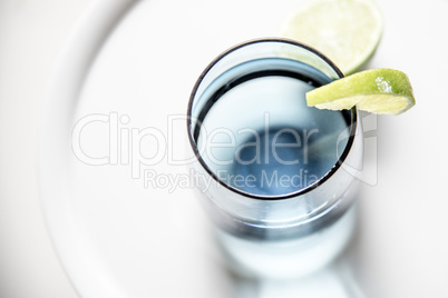 Glass of water with slice of lime, closeup, top view.