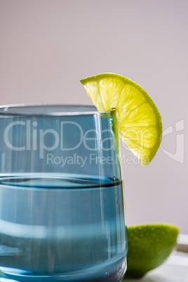 Glass of water with slice of lime, closeup, side view.