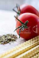 Dry spaghetti, fresh tomatoes and Italian herbs, macro.