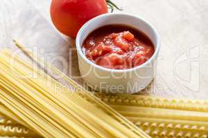 Dry spaghetti, fresh tomato and tomato sauce, closeup.
