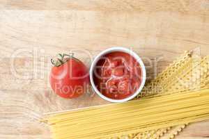 Dry spaghetti, fresh tomato and tomato sauce, top view, room for text.