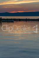 Scenic view of vivid sunset reflection on calm water, silhouette of rowing boat.