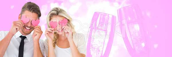 Valentines couple holding hearts over eyes with champagne glasses