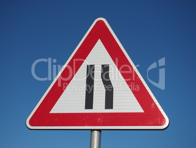 road narrows sign over blue sky