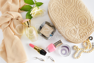 Cosmetics, perfumes, jewelry made of pearls and handbag on a whi