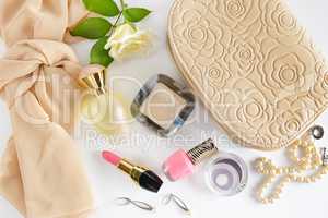 Cosmetics, perfumes, jewelry made of pearls and handbag on a whi