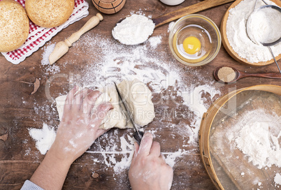 two female hands cut with a knife yeast dough into pieces