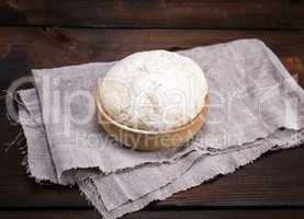 yeast dough in a wooden bowl on a gray napkin