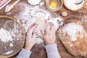 two female hands interfere with a ball of yeast dough