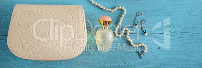 A handbag and a bottle of perfume on a blue wooden background. W