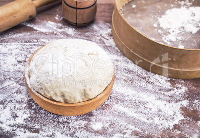 dough made of wheat flour in a wooden bowl on a table