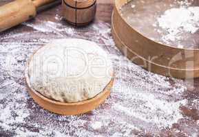dough made of wheat flour in a wooden bowl on a table