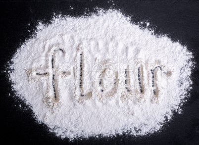 inscription flour on scattered white wheat flour