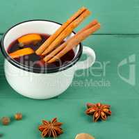 Hot red mulled wine on wooden background with spices, orange sli