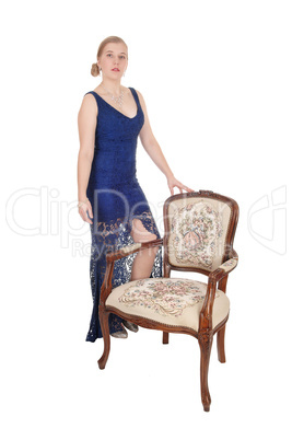 Woman standing in evening gown with armchair