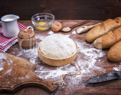 wheat yeast dough for bread and rolls in a wooden bowl