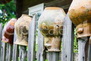 Old broken clay jugs on wooden fence