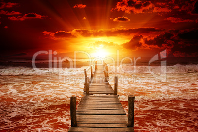 Pier for boats into the sea. Bright sunrise over the ocean.