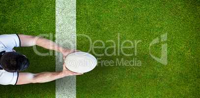 Composite image of high angle view of man holding rugby ball with both hands