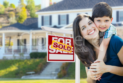 Young Mother and Son In Front of Sold For Sale Real Estate Sign