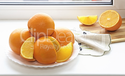 Oranges on a plate on the sill of the window.