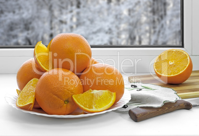 Oranges on a plate on the sill of the window.